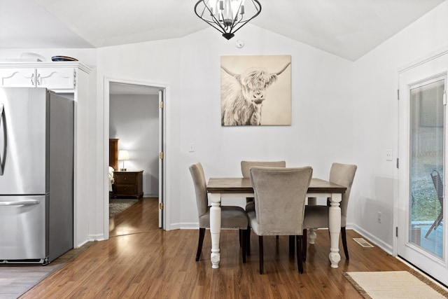 dining area with an inviting chandelier, light hardwood / wood-style flooring, and lofted ceiling