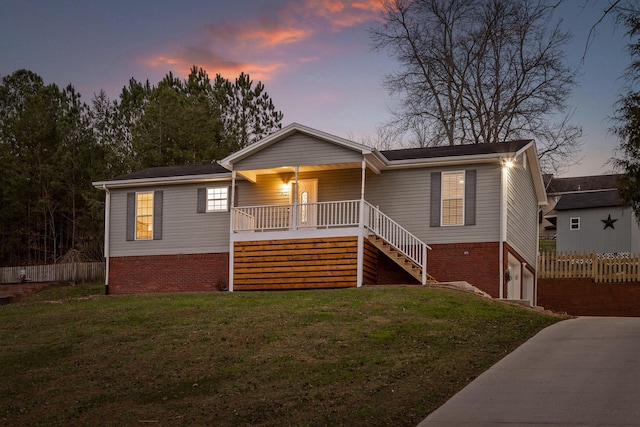 view of front of home featuring a yard, covered porch, and a garage