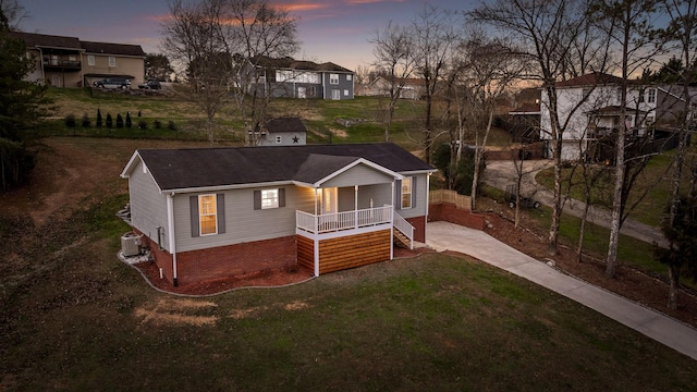 view of front facade featuring a porch, central AC unit, and a lawn