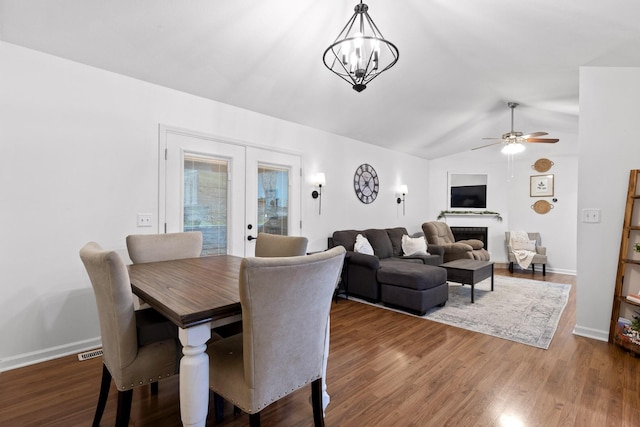 dining space featuring hardwood / wood-style flooring, ceiling fan with notable chandelier, lofted ceiling, and french doors