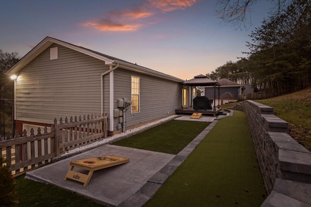 property exterior at dusk featuring a gazebo and a lawn