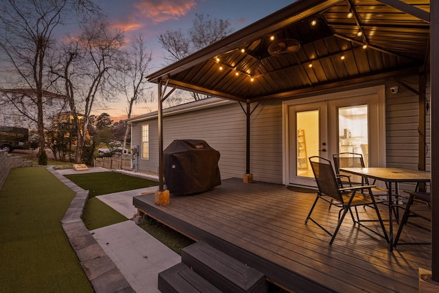 deck at dusk featuring a yard and grilling area