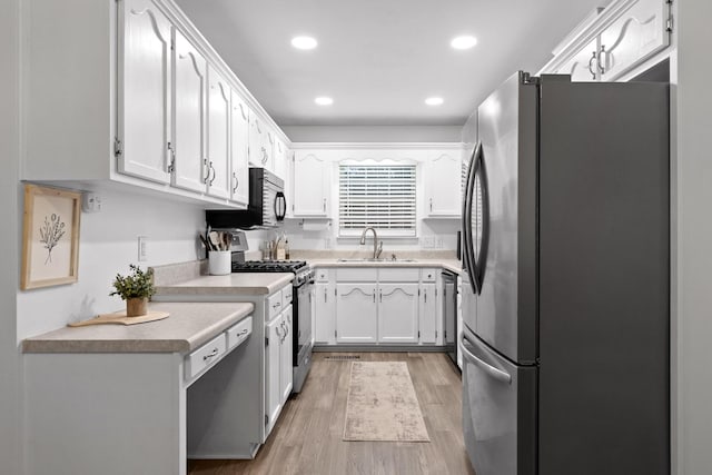 kitchen featuring white cabinetry, sink, appliances with stainless steel finishes, and light hardwood / wood-style flooring