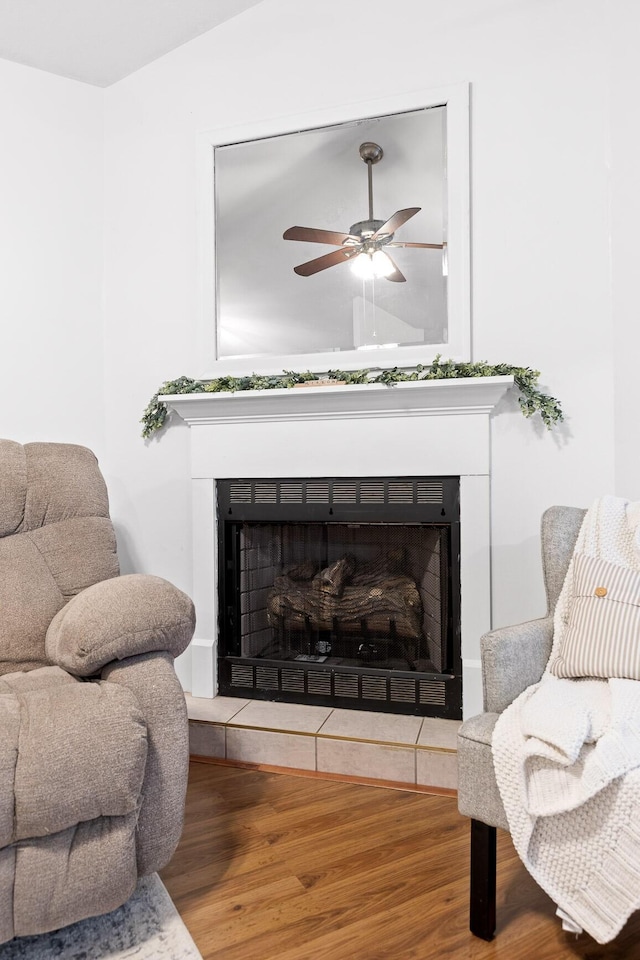 living area featuring hardwood / wood-style floors, ceiling fan, and a fireplace