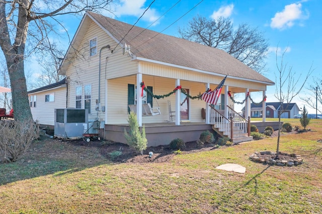 view of front facade with covered porch, central AC unit, and a front lawn