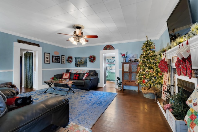 living room featuring dark hardwood / wood-style floors, a brick fireplace, ceiling fan, and crown molding