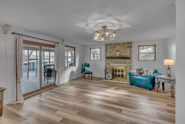 living area with a stone fireplace, wood finished floors, and baseboards