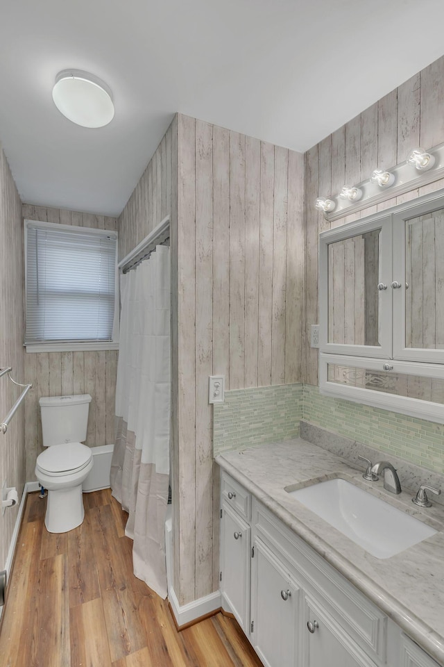 full bathroom featuring shower / bath combo with shower curtain, hardwood / wood-style floors, vanity, and toilet