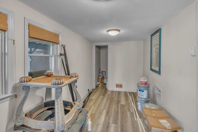 hall featuring visible vents, light wood-style flooring, and baseboards