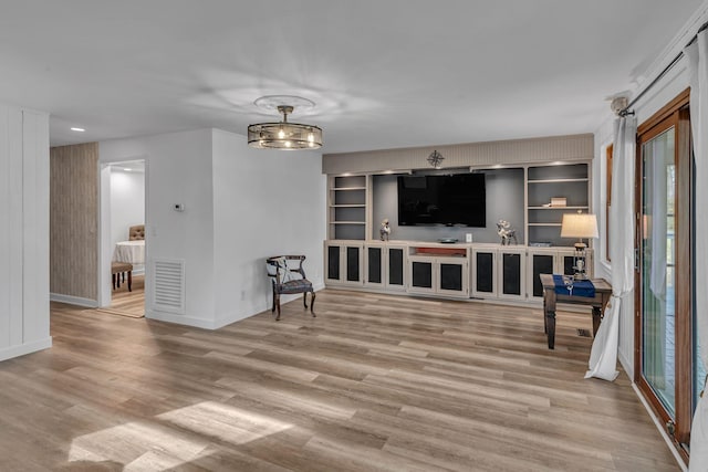 interior space with wood walls, built in features, light wood-type flooring, and an inviting chandelier