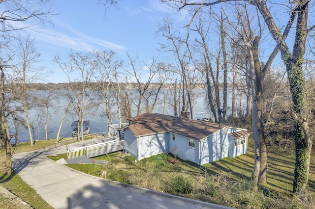 exterior space featuring a water view, concrete driveway, and fence