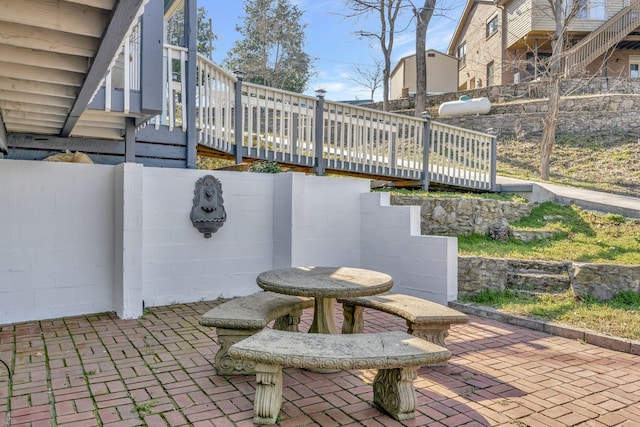 view of patio with outdoor dining space, a deck, and fence