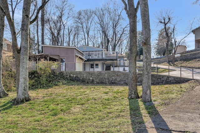 view of front of property with a wooden deck, a front lawn, and fence