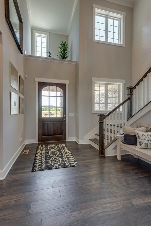 entrance foyer with crown molding, a towering ceiling, and dark wood-type flooring