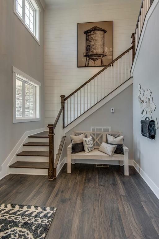 stairs with plenty of natural light, a high ceiling, and hardwood / wood-style flooring