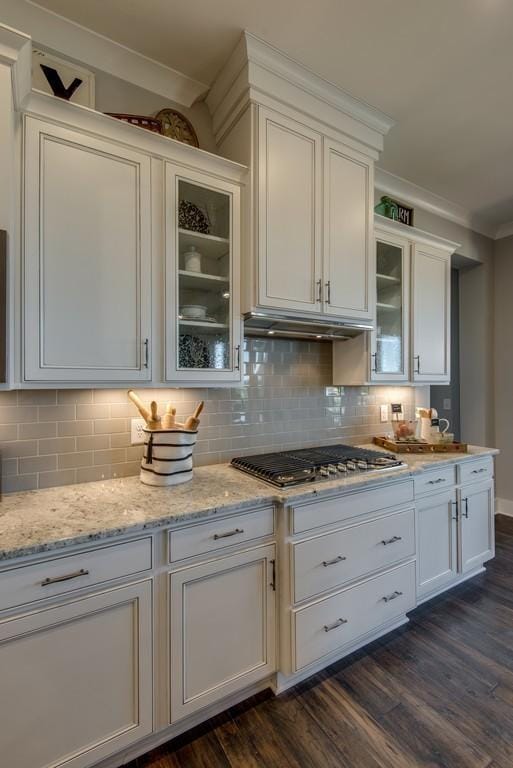 kitchen featuring light stone countertops, stainless steel gas cooktop, dark hardwood / wood-style flooring, backsplash, and white cabinets