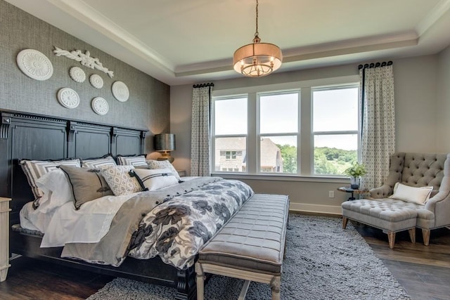 bedroom with a tray ceiling, crown molding, and dark hardwood / wood-style flooring