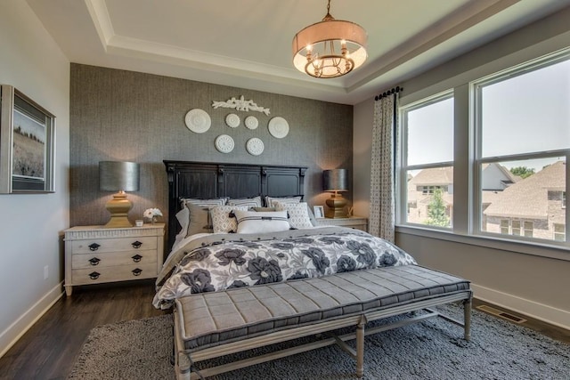 bedroom with dark hardwood / wood-style floors, multiple windows, a chandelier, and a tray ceiling