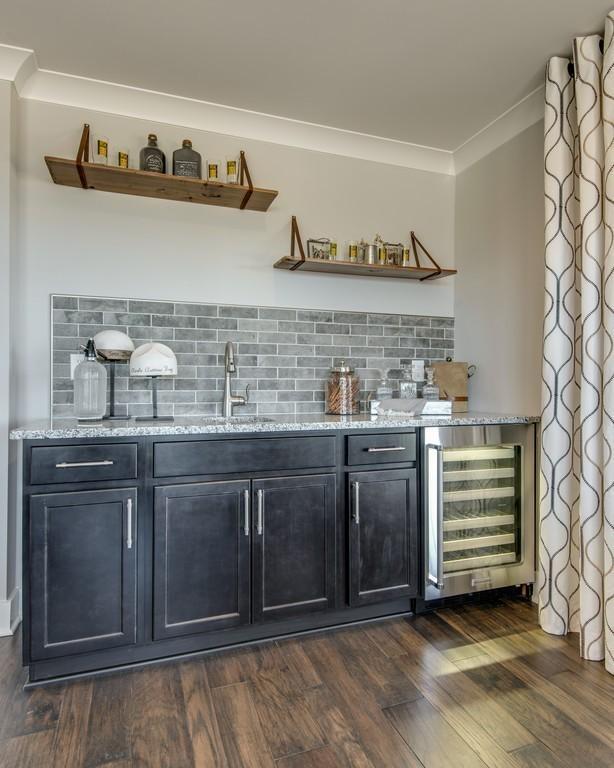 bar featuring sink, dark hardwood / wood-style floors, light stone countertops, tasteful backsplash, and beverage cooler