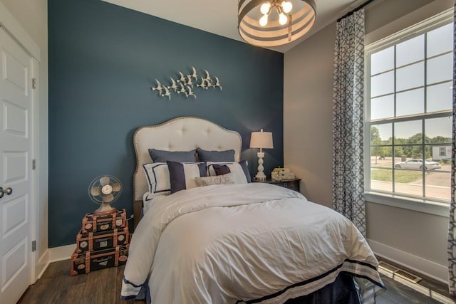 bedroom with dark hardwood / wood-style flooring and an inviting chandelier