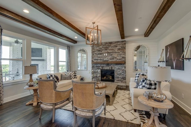 living room featuring beam ceiling, a fireplace, hardwood / wood-style floors, and ceiling fan with notable chandelier