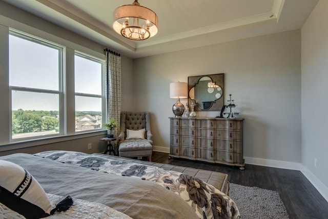 bedroom featuring a tray ceiling, multiple windows, a chandelier, and dark wood-type flooring