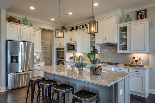 kitchen featuring white cabinets, a kitchen bar, stainless steel appliances, and a kitchen island with sink