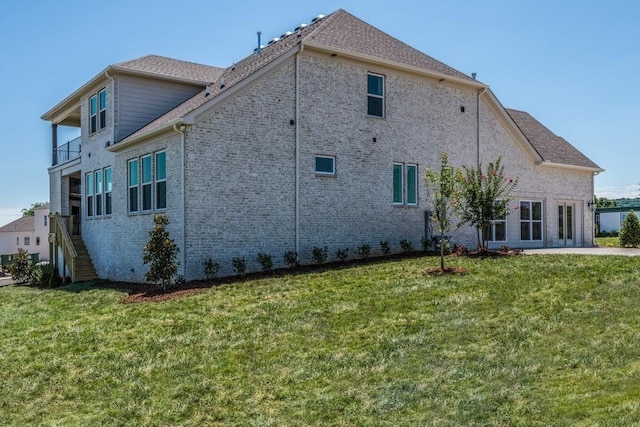 rear view of property featuring a balcony and a lawn