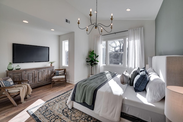 bedroom with light hardwood / wood-style flooring, vaulted ceiling, and a notable chandelier