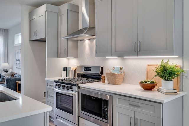 kitchen with sink, decorative backsplash, wall chimney range hood, and appliances with stainless steel finishes