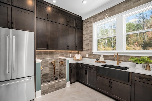 kitchen with stainless steel fridge, sink, and dark brown cabinets