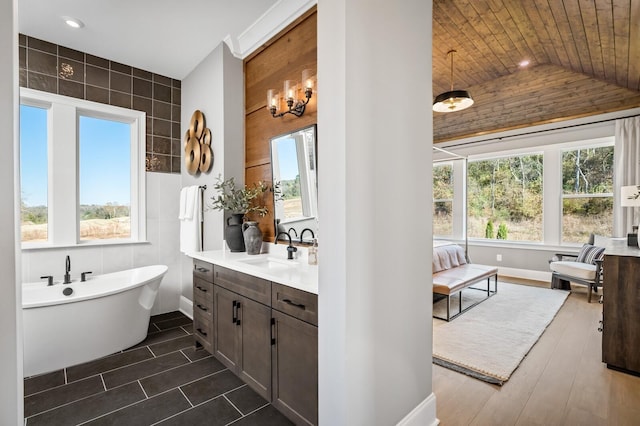 bathroom featuring vanity, a healthy amount of sunlight, wooden ceiling, and a tub