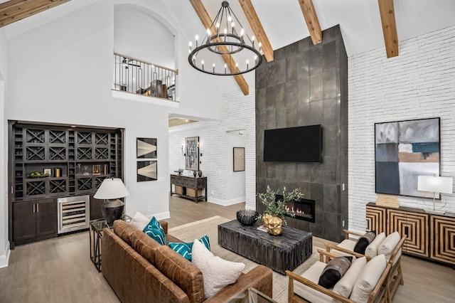 living room with beamed ceiling, a towering ceiling, light hardwood / wood-style flooring, and a tile fireplace