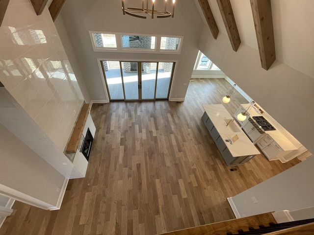 unfurnished living room featuring beamed ceiling, a towering ceiling, dark hardwood / wood-style floors, and a chandelier