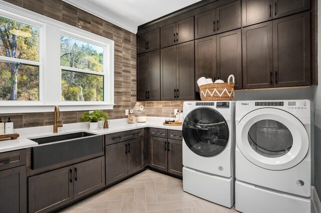 washroom with cabinets, light parquet flooring, washer and clothes dryer, and sink