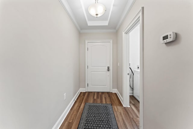 doorway to outside with a raised ceiling, wood-type flooring, and crown molding