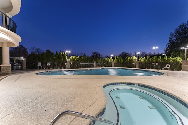 pool at twilight featuring a hot tub and a patio area