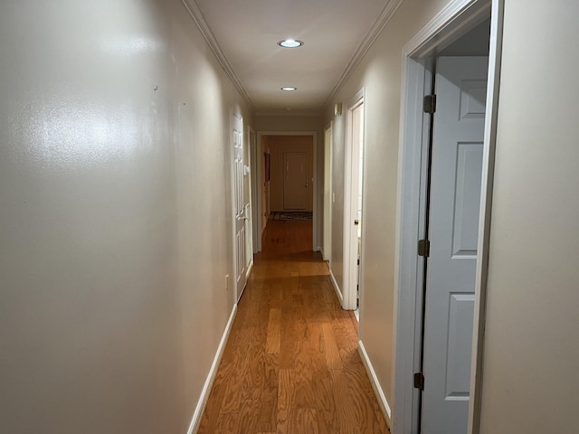 hallway with light wood-type flooring and ornamental molding