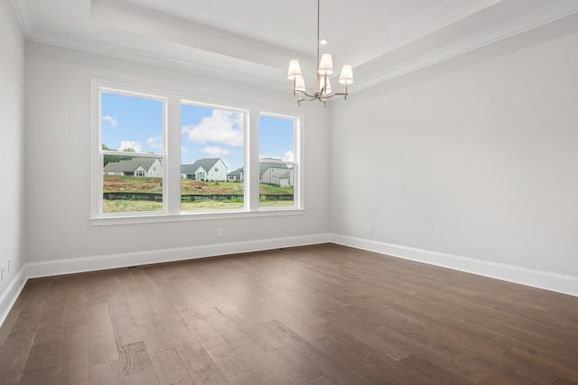 unfurnished room with a raised ceiling, ornamental molding, dark wood-type flooring, and an inviting chandelier