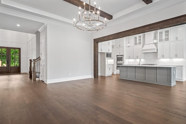 kitchen with white cabinets, an island with sink, hanging light fixtures, and custom exhaust hood