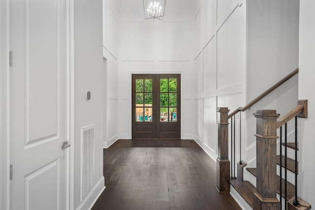 foyer with french doors, dark wood-type flooring, and an inviting chandelier