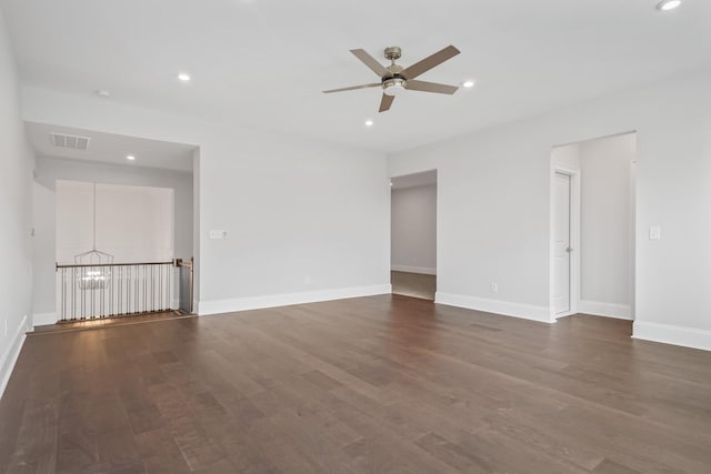 spare room with dark hardwood / wood-style flooring and ceiling fan with notable chandelier