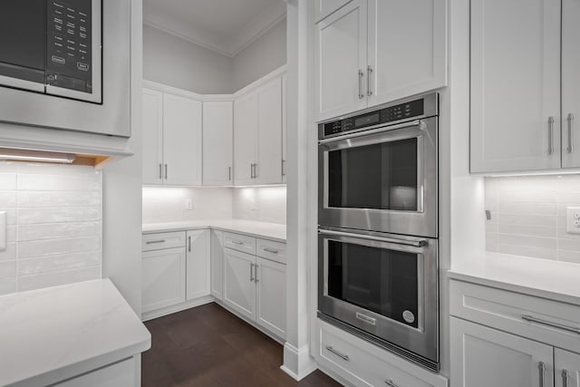 kitchen with appliances with stainless steel finishes, tasteful backsplash, ornamental molding, white cabinets, and dark hardwood / wood-style floors