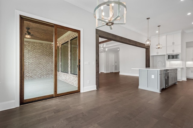 kitchen featuring ceiling fan with notable chandelier, decorative light fixtures, a center island with sink, white cabinets, and stainless steel microwave