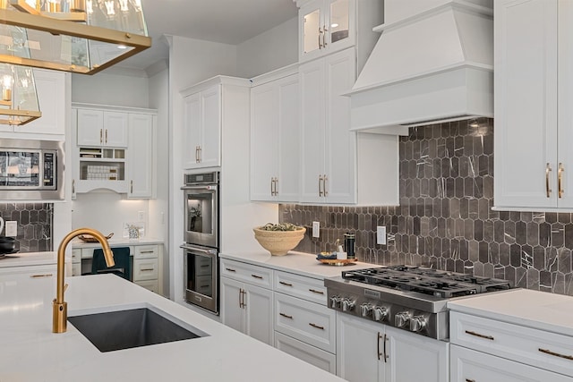 kitchen featuring white cabinetry, decorative backsplash, custom range hood, and appliances with stainless steel finishes