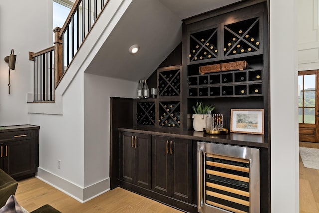 wine area with indoor bar, beverage cooler, and light hardwood / wood-style flooring