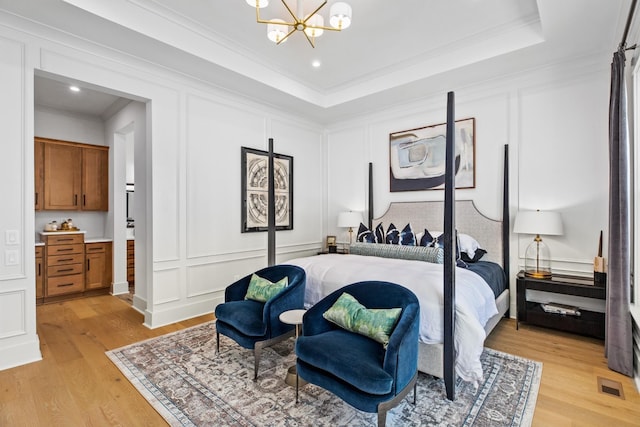 bedroom featuring a raised ceiling, crown molding, and light hardwood / wood-style flooring