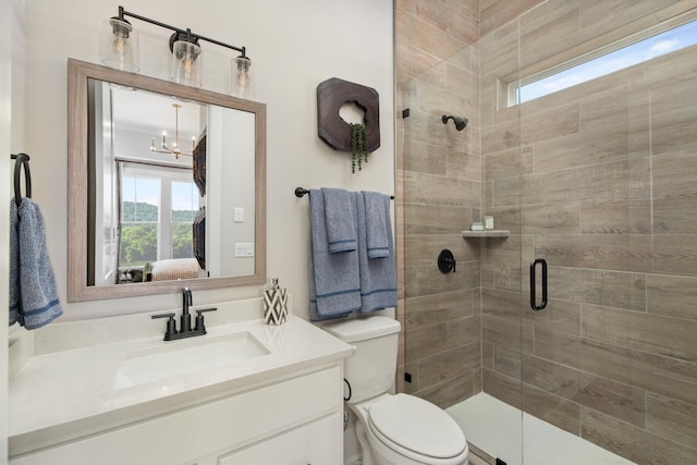 bathroom featuring vanity, toilet, an enclosed shower, and a notable chandelier