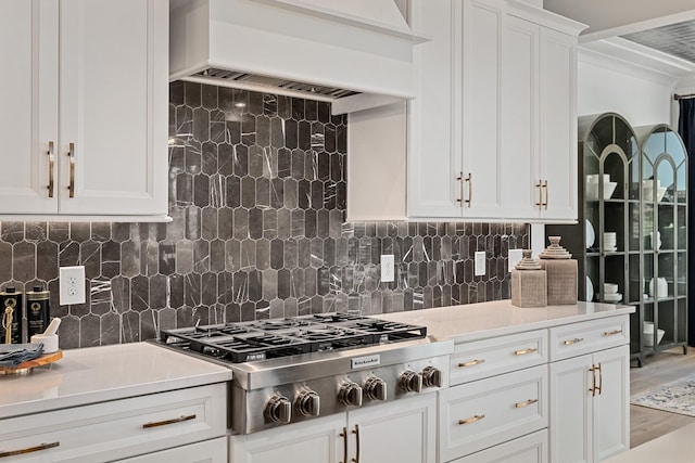 kitchen featuring stainless steel gas cooktop, white cabinetry, tasteful backsplash, and ventilation hood