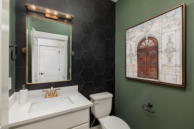 bathroom featuring vanity, toilet, and tile walls